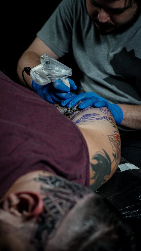 Tattoo artist creating detailed ink design on client's arm.