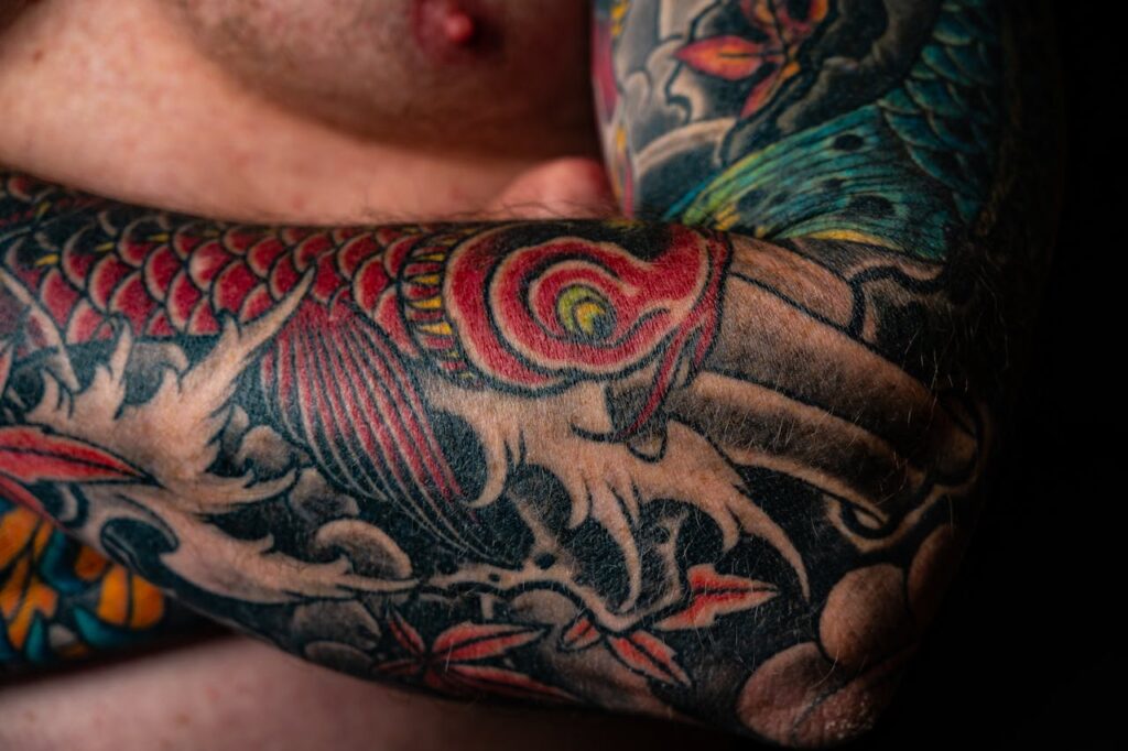 Close-up of a colorful Japanese style tattoo on a man's arm, featuring dragons and vibrant colors.