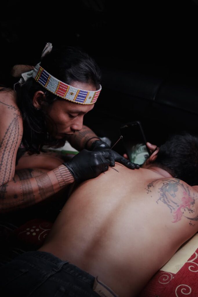 A traditional tattoo artist in West Java creates intricate body art on a client's back.