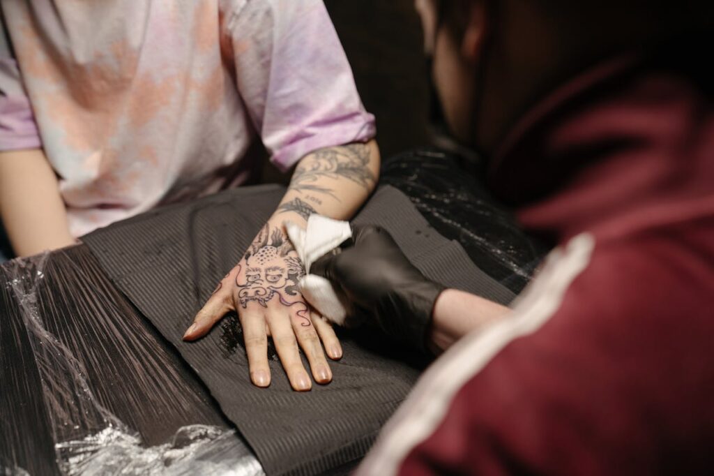 Close-up of a tattoo artist creating a detailed hand tattoo in a professional studio.
