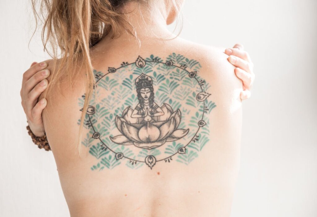 A close-up of a stunning Buddha tattoo on a woman's back, showcasing intricate design details.