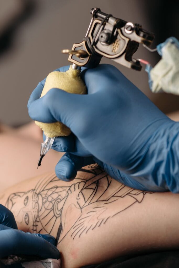 Close-up of a tattoo artist using a tattoo machine to create detailed skin art.